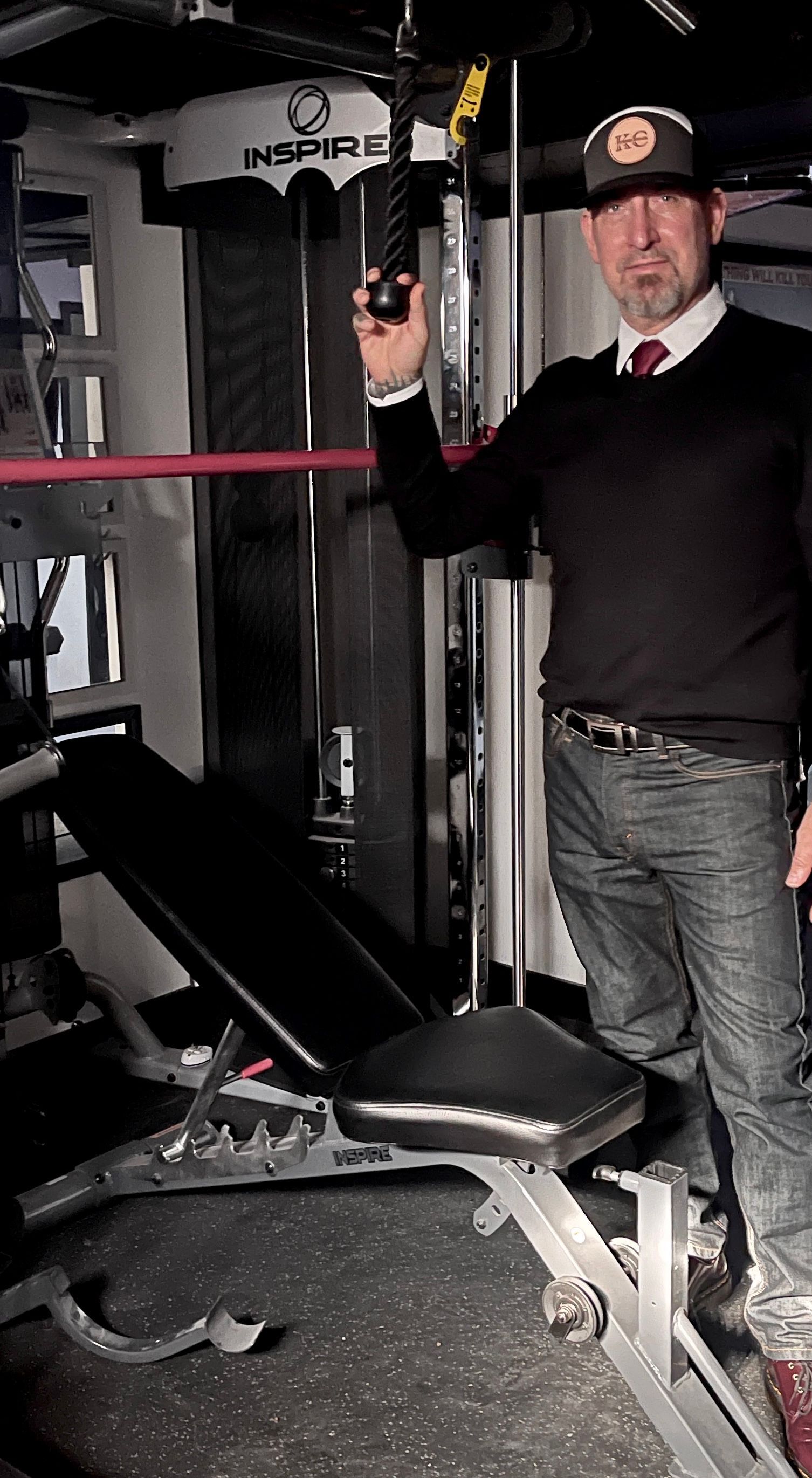A man is standing in a gym holding a rope.