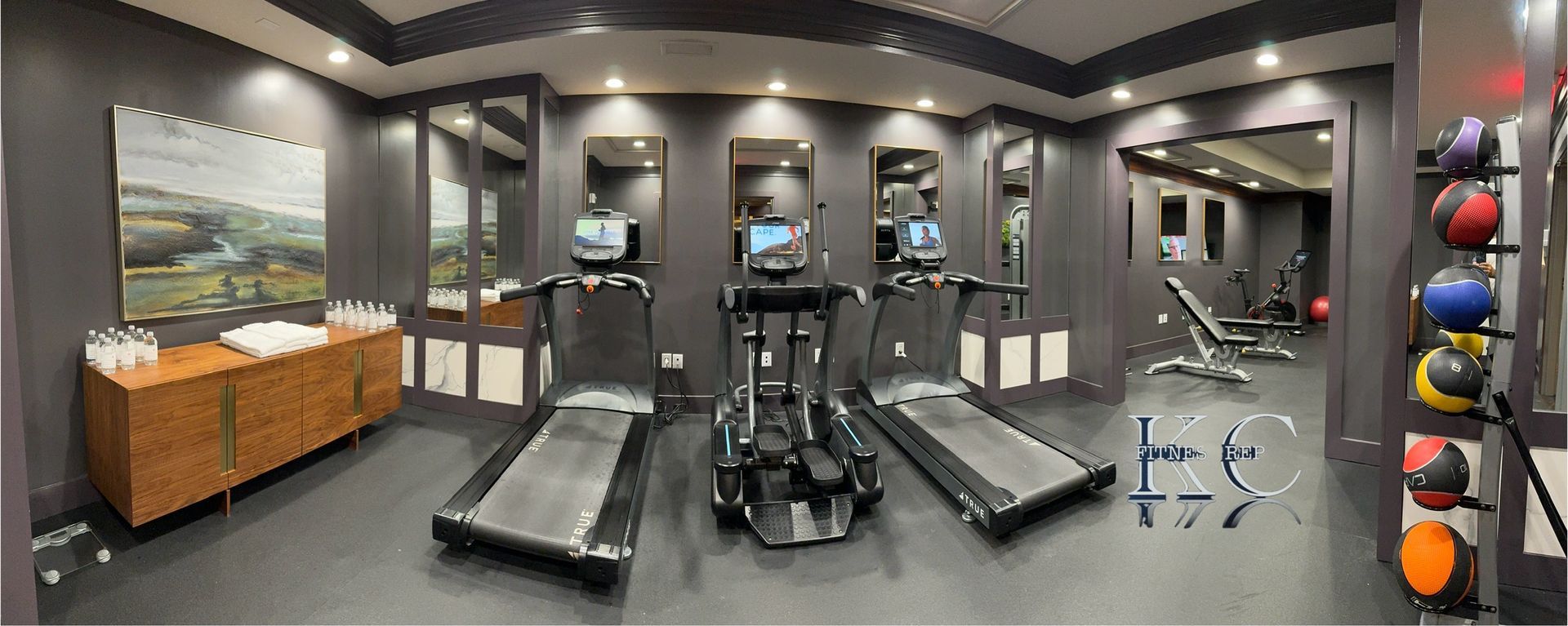 A gym with treadmills , exercise balls , and a painting on the wall.