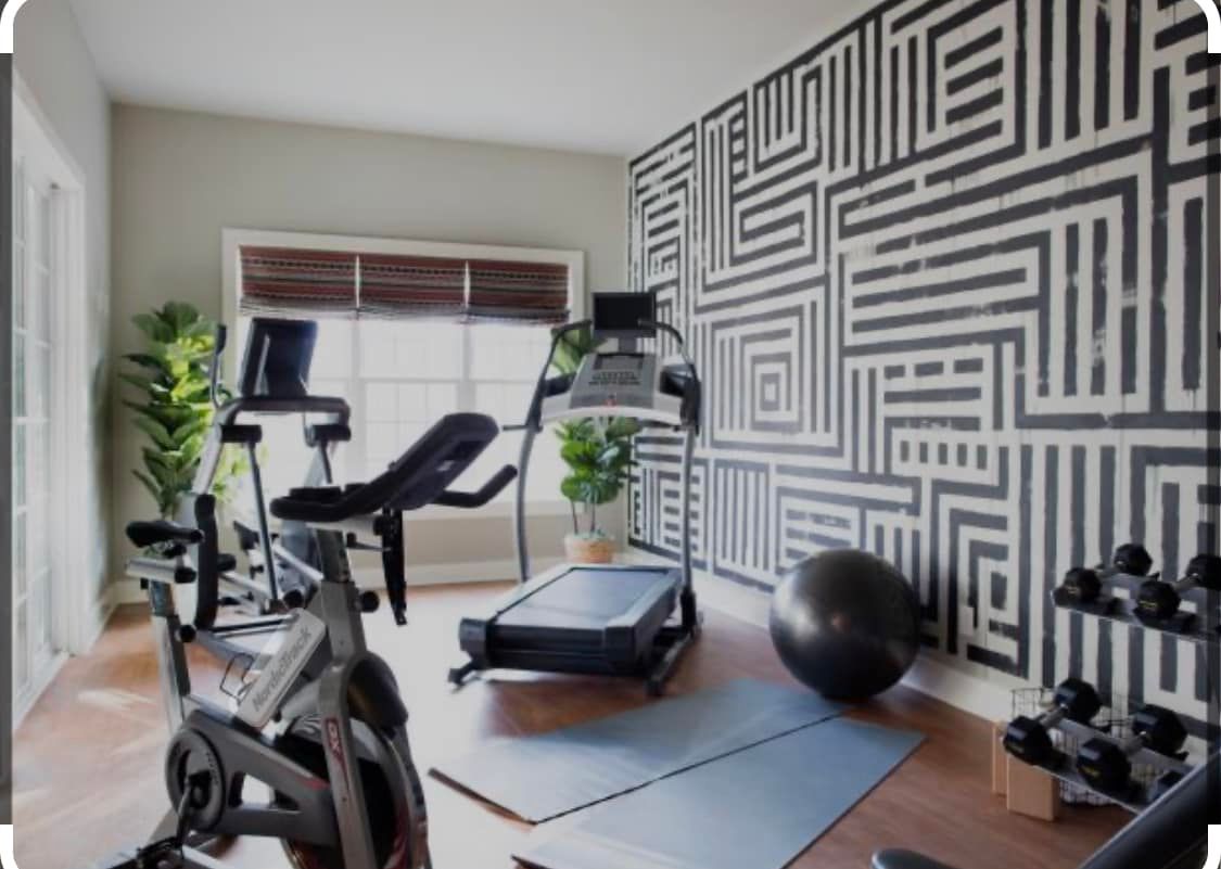 A home gym with a treadmill , exercise bike , dumbbells and a yoga ball.