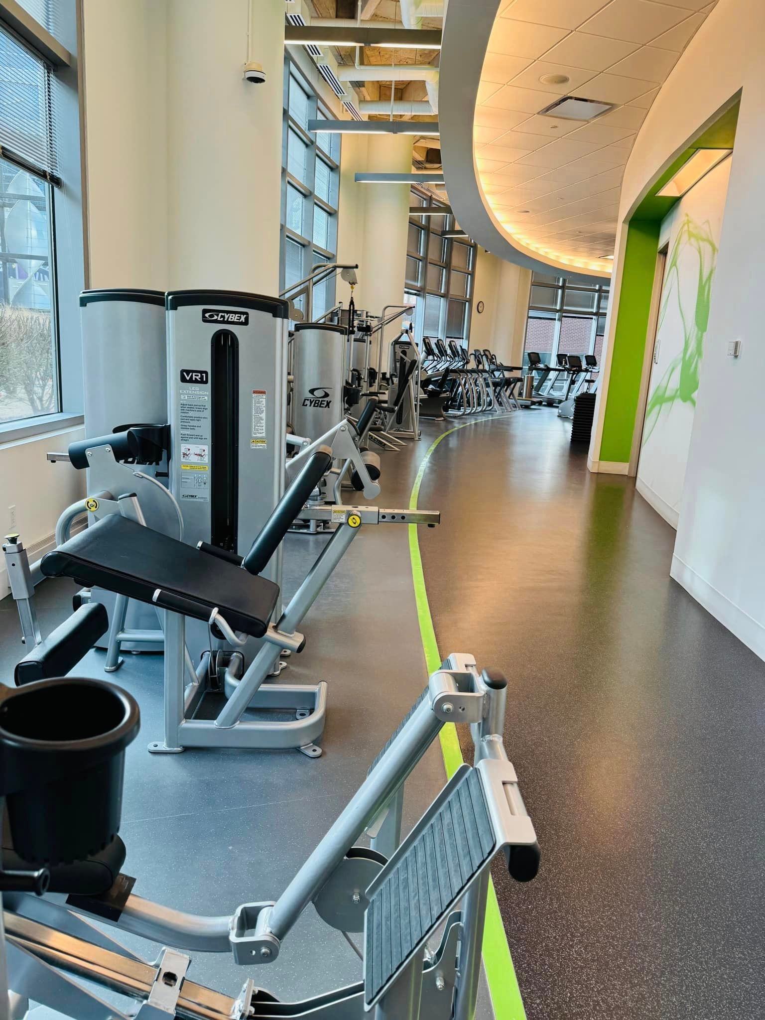 A gym with a lot of exercise equipment and a green line on the floor.