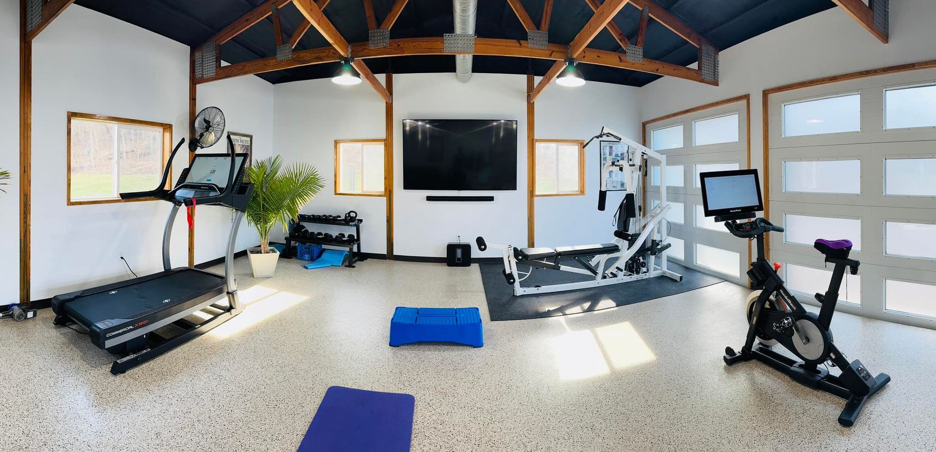 A home gym with a treadmill , exercise bike , and television.
