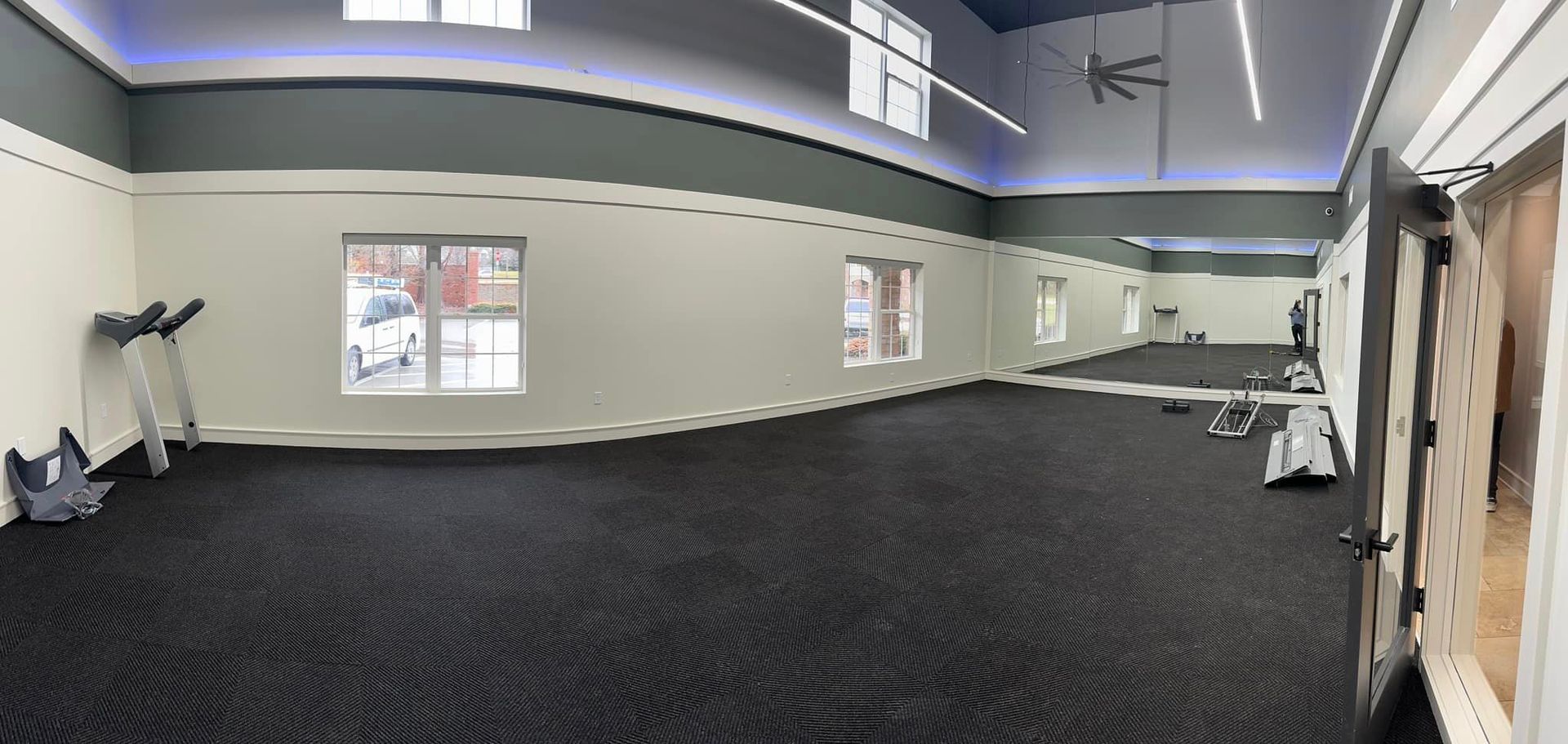 A large empty gym with a lot of mirrors and exercise equipment.