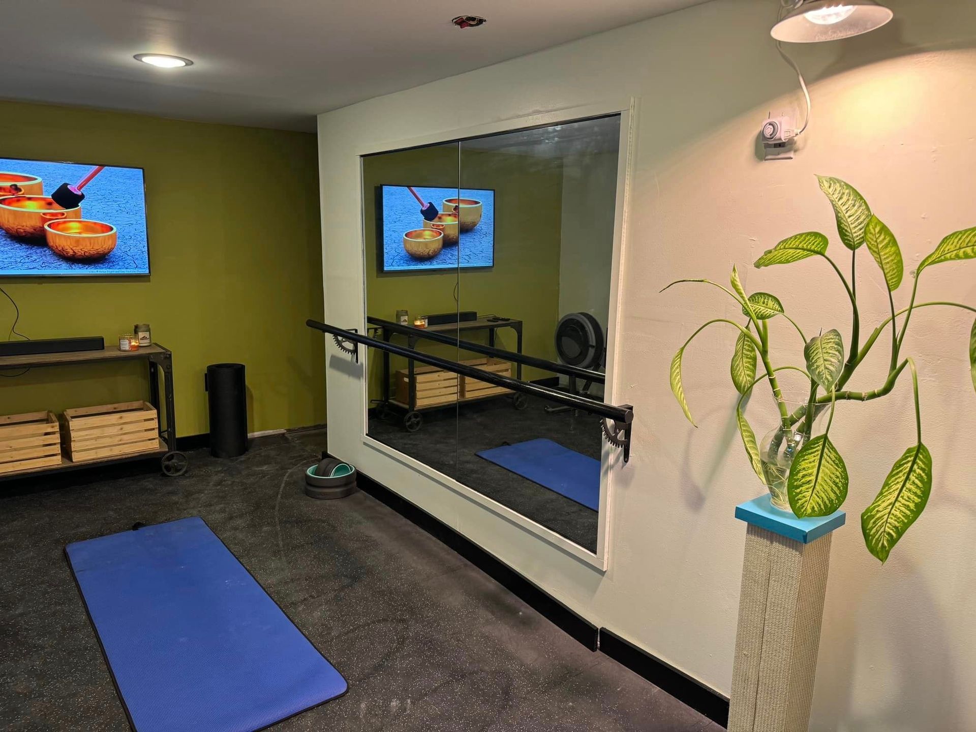 A room with a large mirror and two televisions on the wall