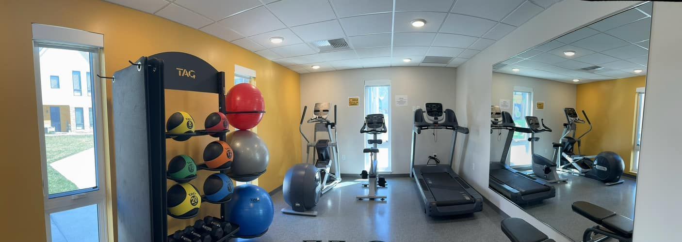 A gym with a treadmill , exercise balls , and a large mirror.