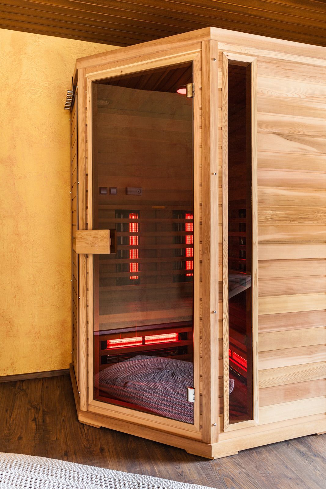 A wooden sauna is sitting on a wooden floor in a room.