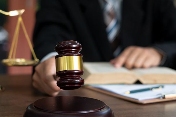 A judge's gavel in focus with a blurred background of a person.