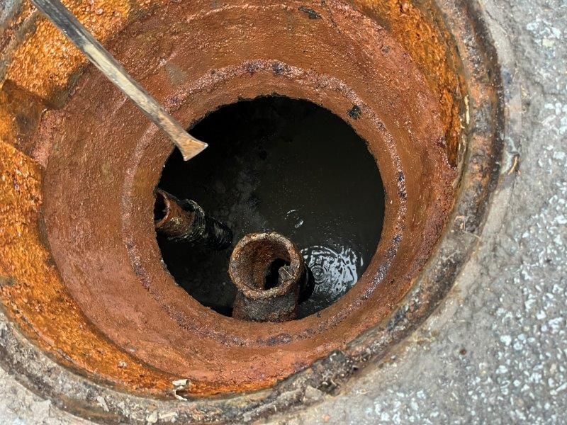 Hands connecting pipes, plumbing repair against brick wall.