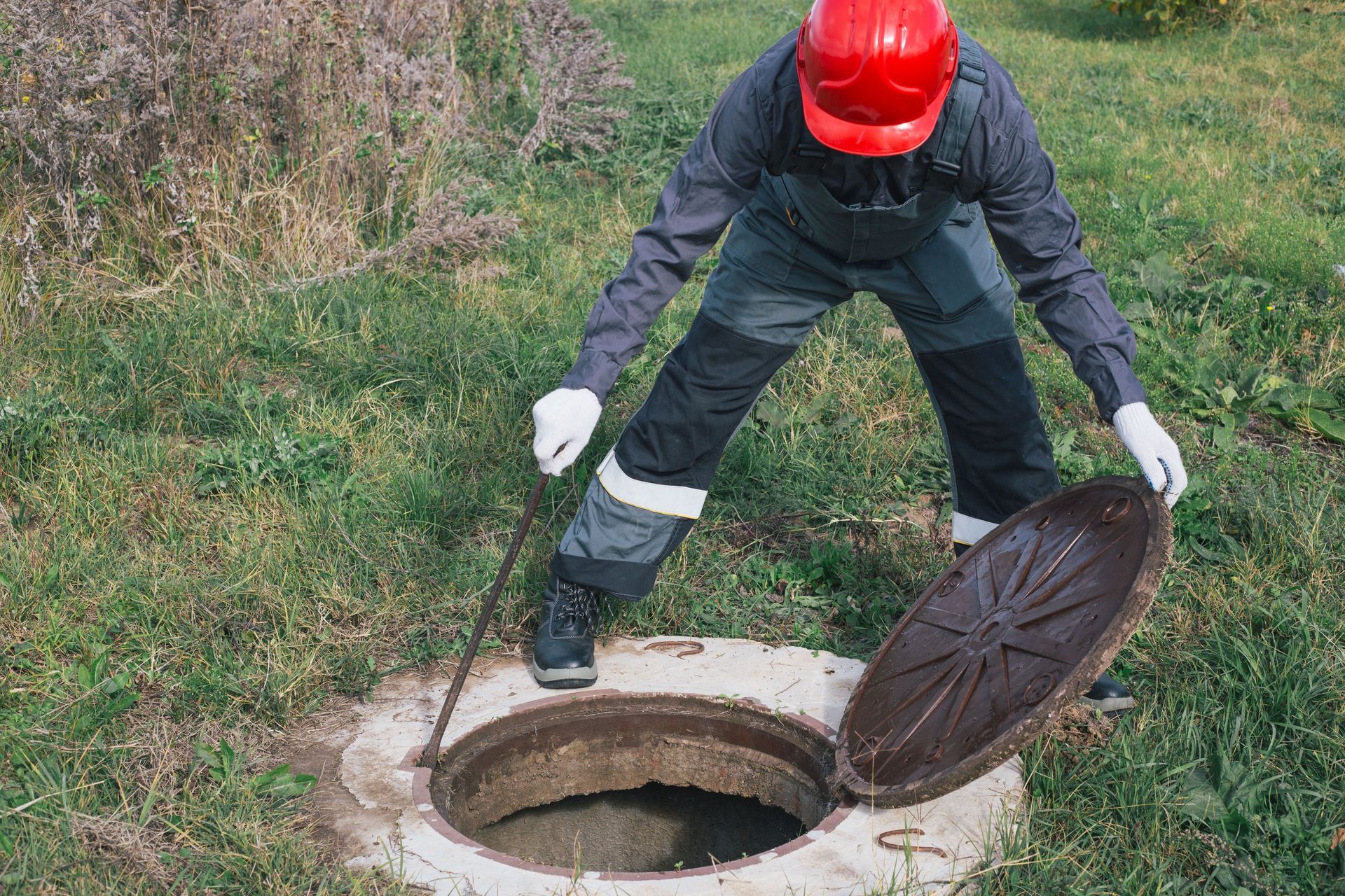 Worker opens septic well manhole cover. Worker opens septic well manhole cover.