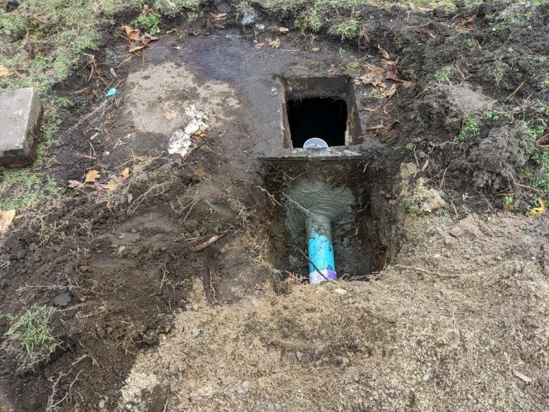 Bathroom sink plumbing, black and white, with a curved pipe and visible water droplets.