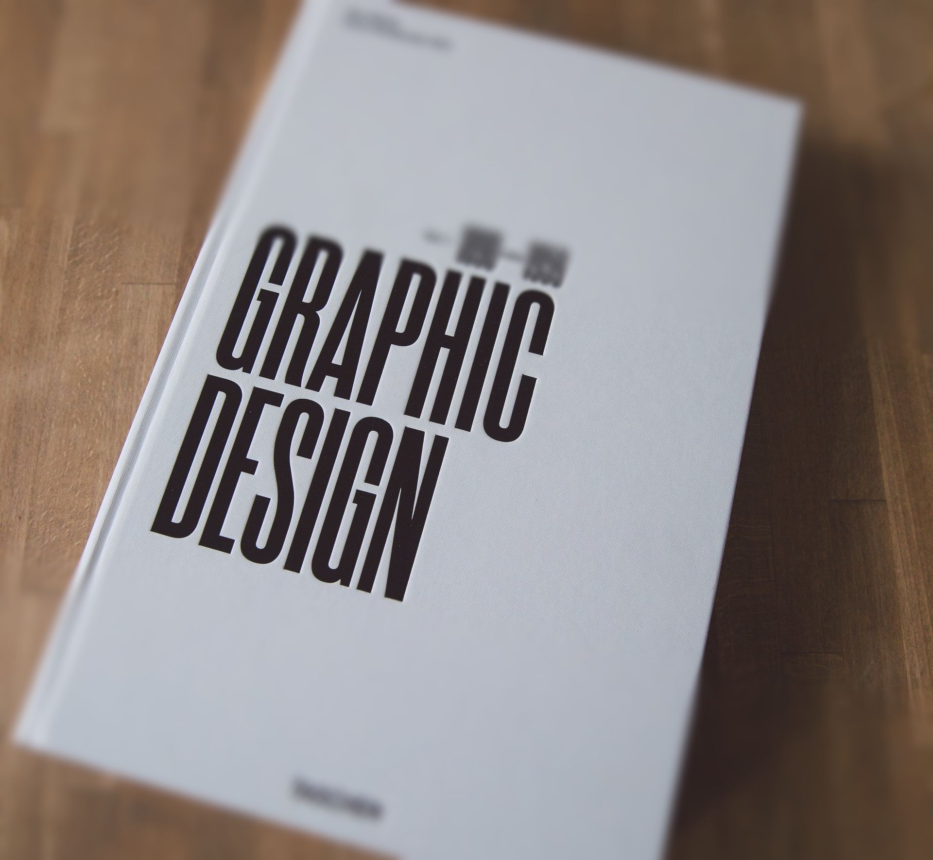 A book titled graphic design sits on a wooden table