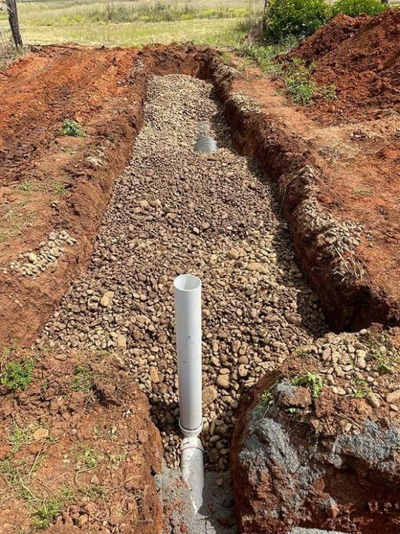 A White Pipe Is Sitting In The Middle Of A Pile Of Gravel — BJB Plumbing & Gasfitting in Dubbo, NSW