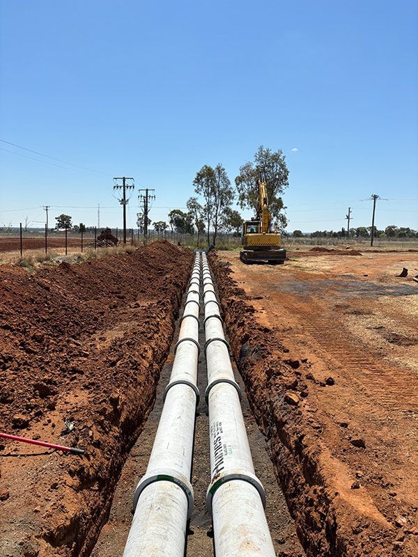 A Row of Pipes Are Being Installed in A Dirt Field — BJB Plumbing & Gasfitting in Bourke, NSW