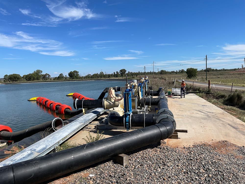 A Bunch of Pipes Are Sitting Next to A Body of Water — BJB Plumbing & Gasfitting in Parkes, NSW