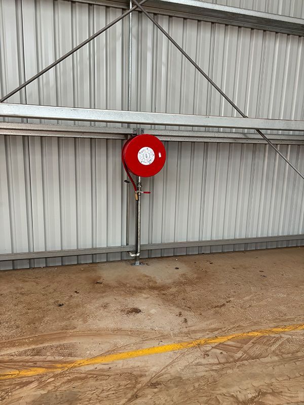 A Red Fire Hose Is Attached to The Side of A Building — BJB Plumbing & Gasfitting in Dubbo, NSW