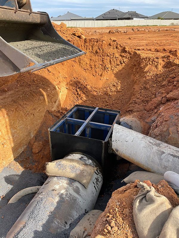 A Bucket Of Dirt Is Being Poured Into A Hole In The Ground — BJB Plumbing & Gasfitting in Dubbo, NSW