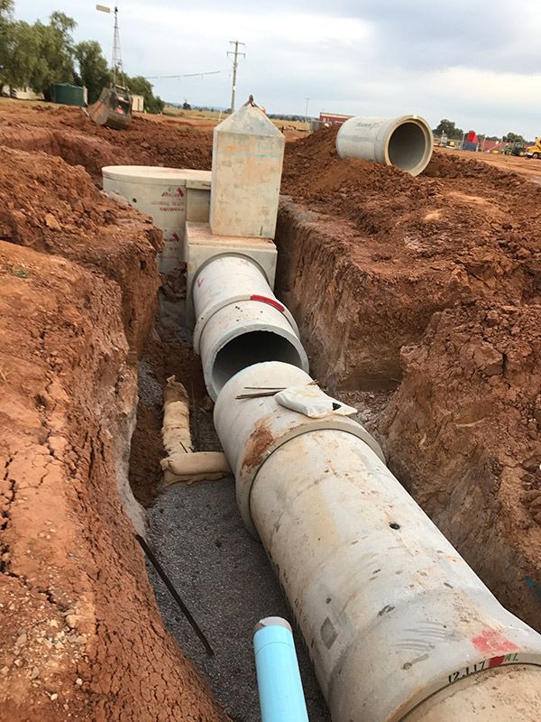 A Bunch of Pipes Are Laying in The Dirt in A Trench — BJB Plumbing & Gasfitting in Cobar, NSW