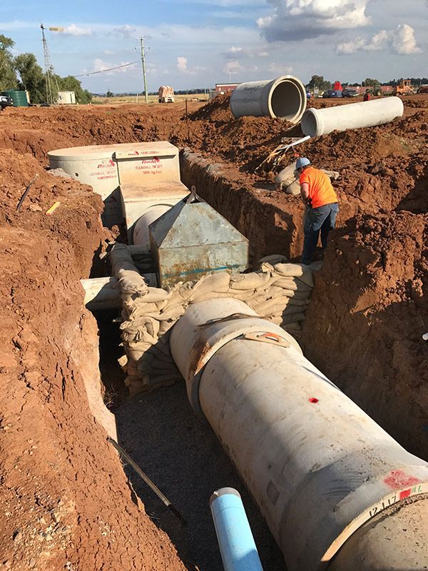A Man Is Working on A Pipe in The Dirt — BJB Plumbing & Gasfitting in Bourke, NSW
