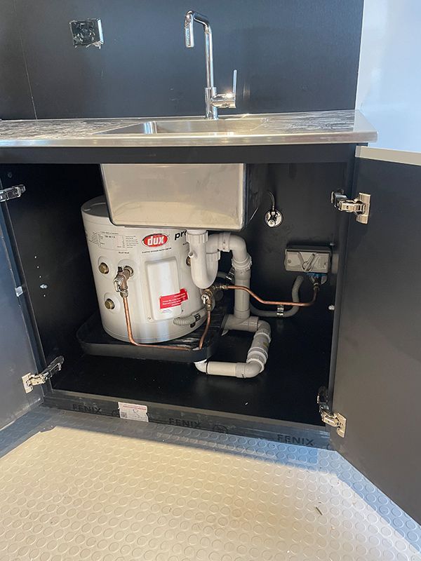 A Water Heater Is Sitting Under A Sink In A Cabinet — BJB Plumbing & Gasfitting in Dubbo, NSW