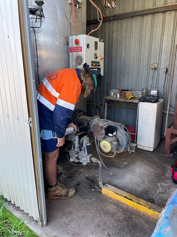 A Man Is Working On A Machine In A Shed — BJB Plumbing & Gasfitting in Dubbo, NSW