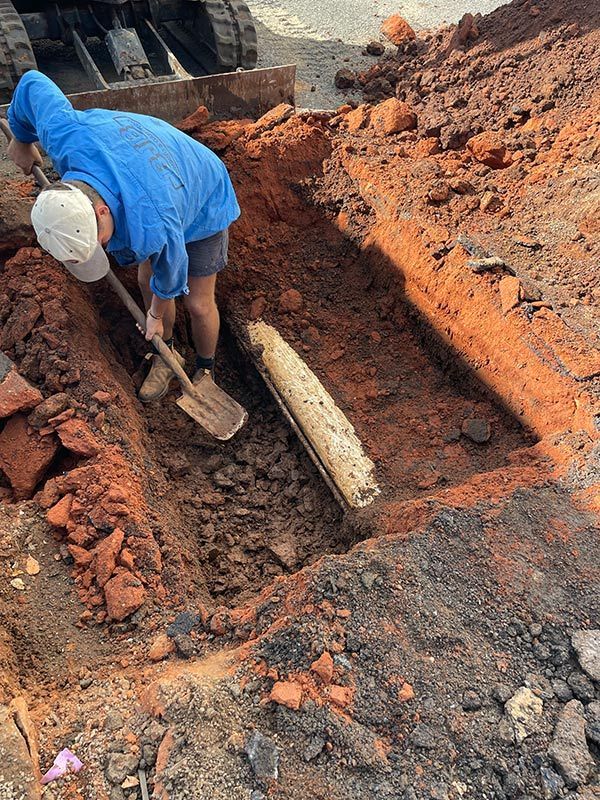A Man Is Digging a Hole in The Ground with A Shovel — BJB Plumbing & Gasfitting in Parkes, NSW