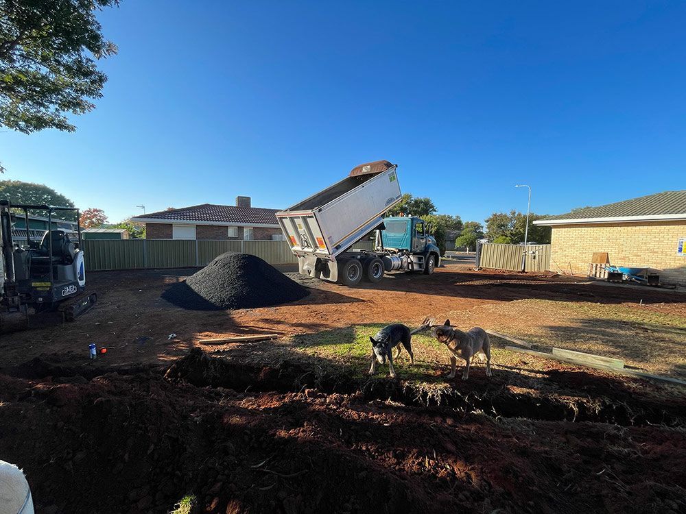 In a Yard, Dirt Is Being Loaded onto A Dump Truck — BJB Plumbing & Gasfitting in Dubbo, NSW