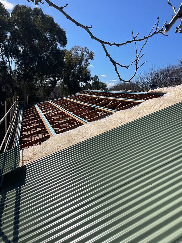 A Green Corrugated Metal Roof with A Tree in The Background — BJB Plumbing & Gasfitting in Dubbo, NSW