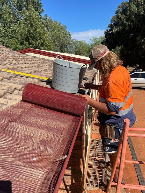 A Man Is Standing on A Ladder Working on A Roof — BJB Plumbing & Gasfitting in Cobar, NSW
