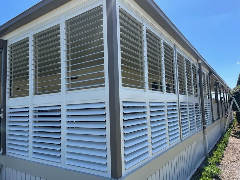 The corner of a house from the outside. Both sides have outdoors blinds on all windows.