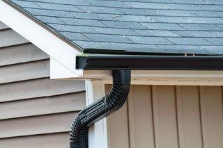 A close up of a gutter on the side of a house.