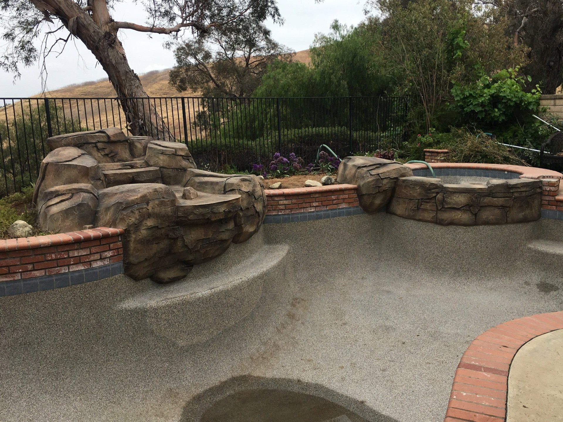 A swimming pool with a hot tub and a tree in the background