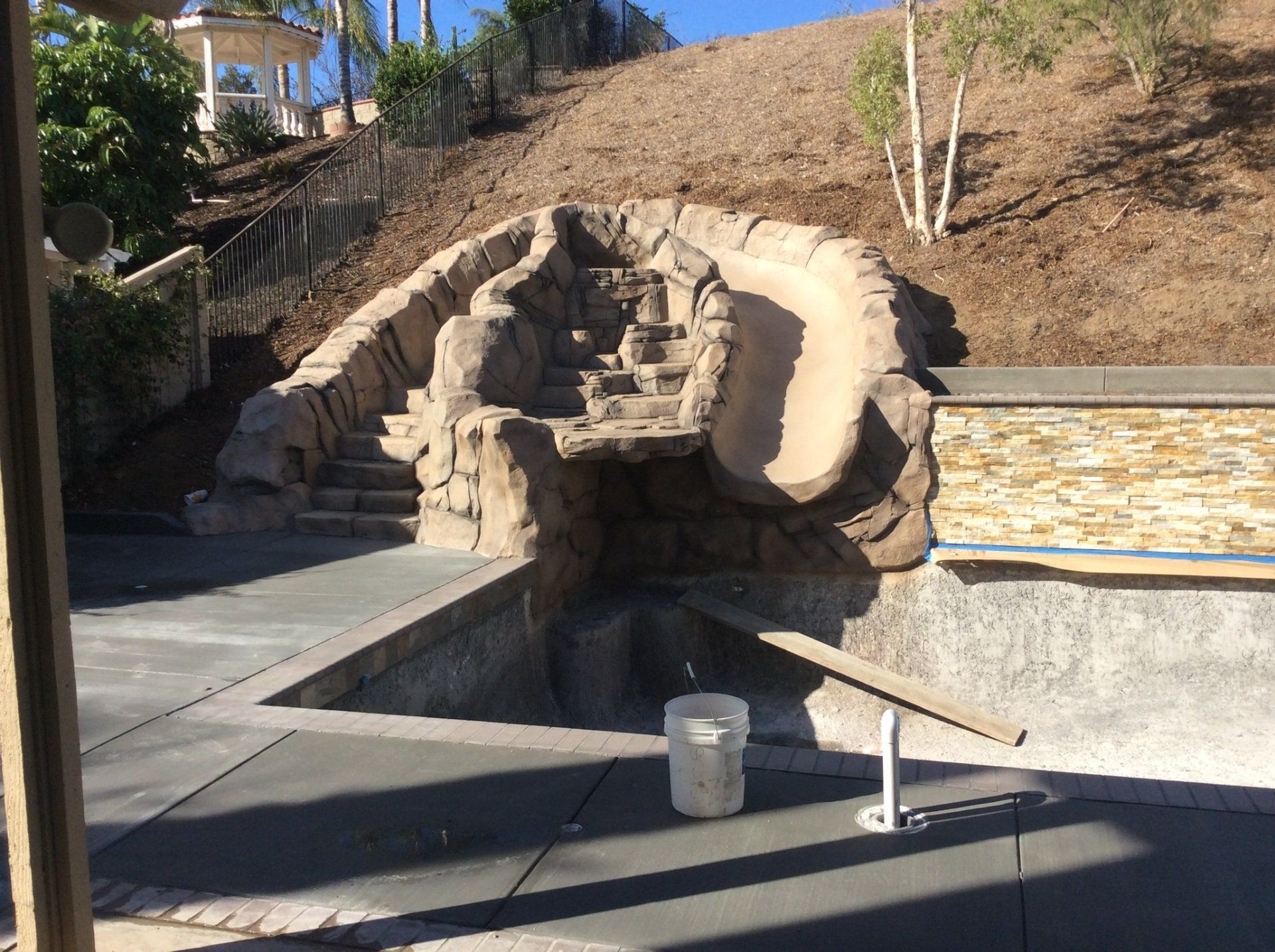 A water slide is being built next to a swimming pool.