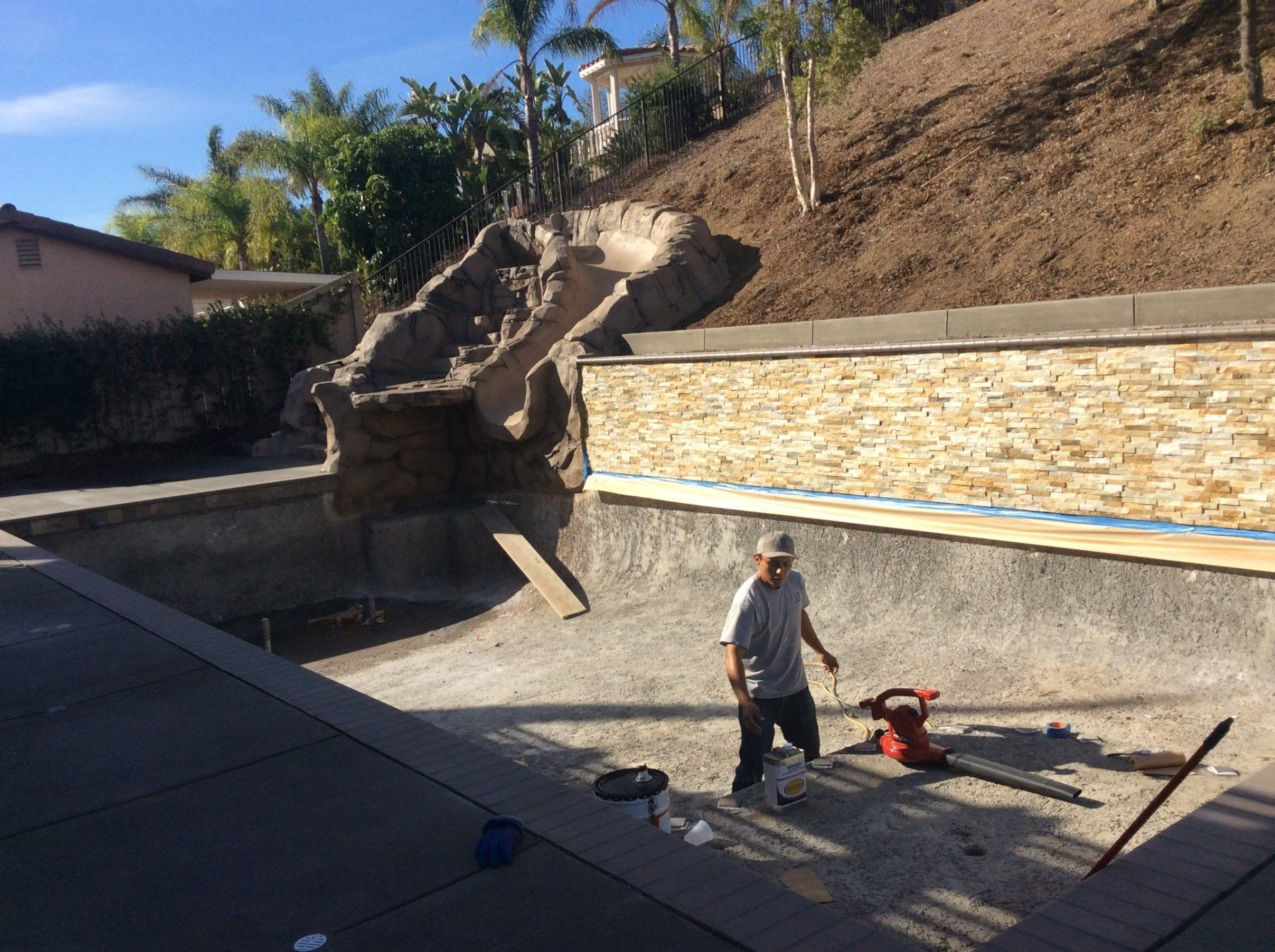 A man is standing in front of a swimming pool under construction