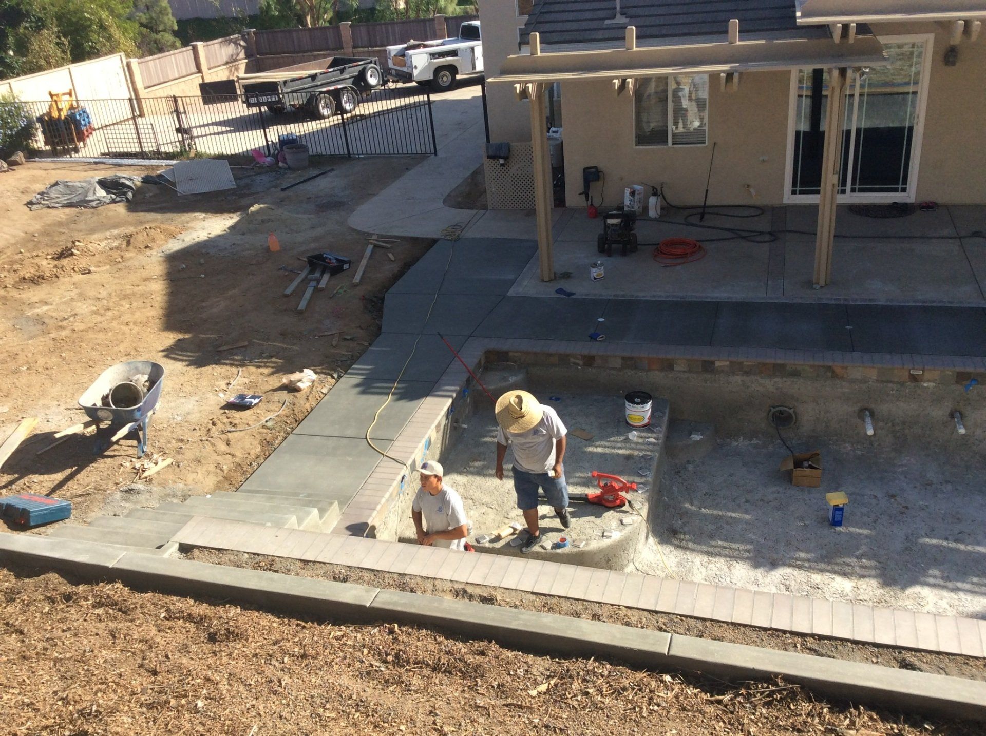 A man is working on a concrete walkway in front of a house.