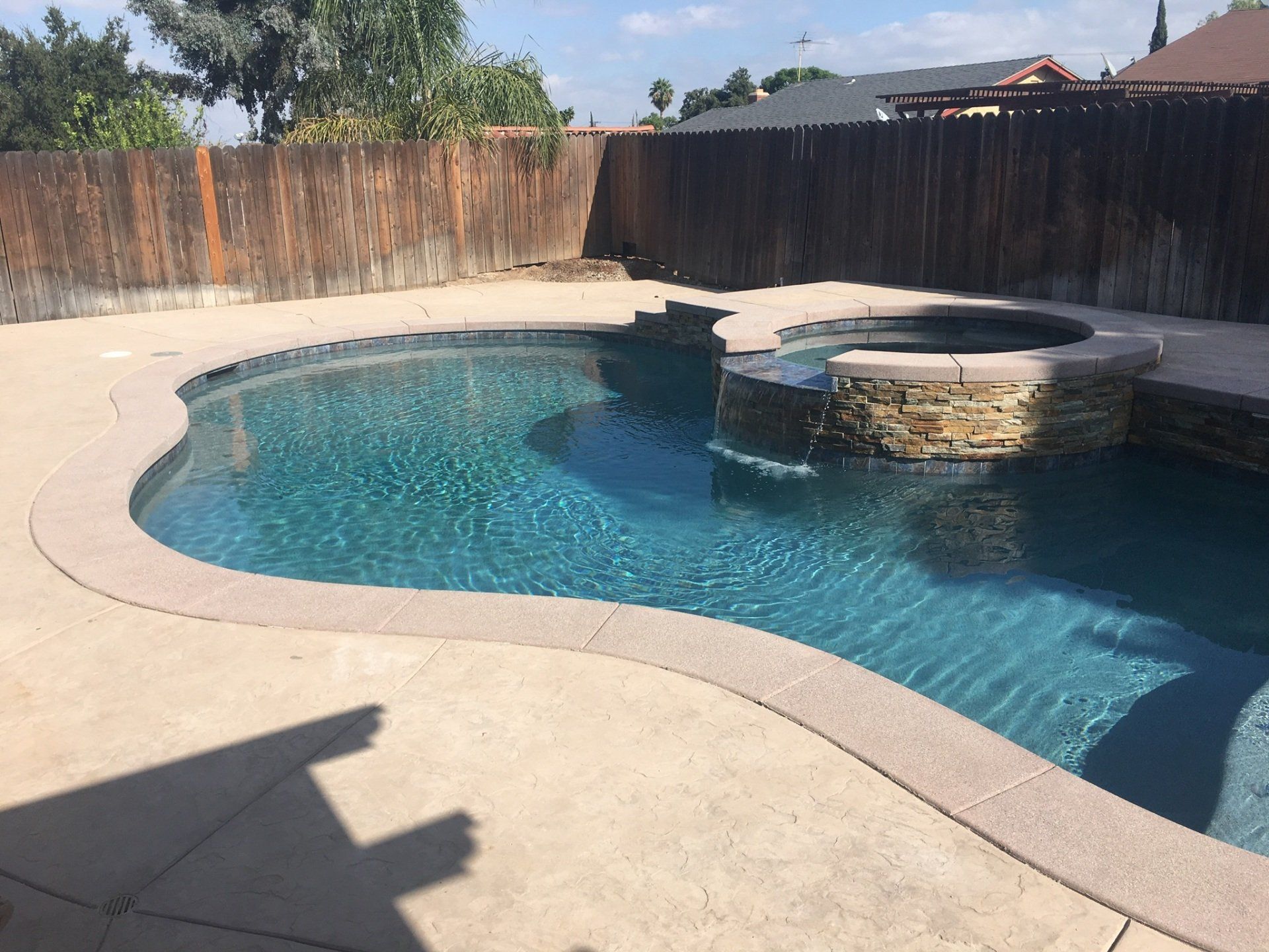 A large swimming pool is surrounded by a wooden fence.