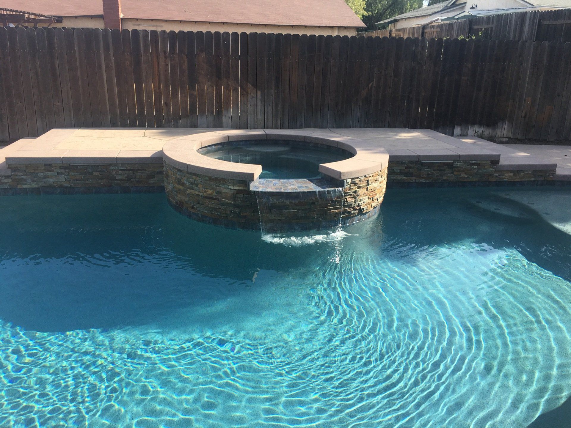 A large swimming pool with a hot tub in the middle of it.