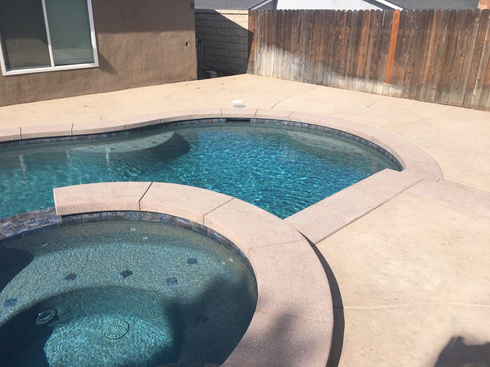 A large swimming pool with a hot tub in the middle of it.