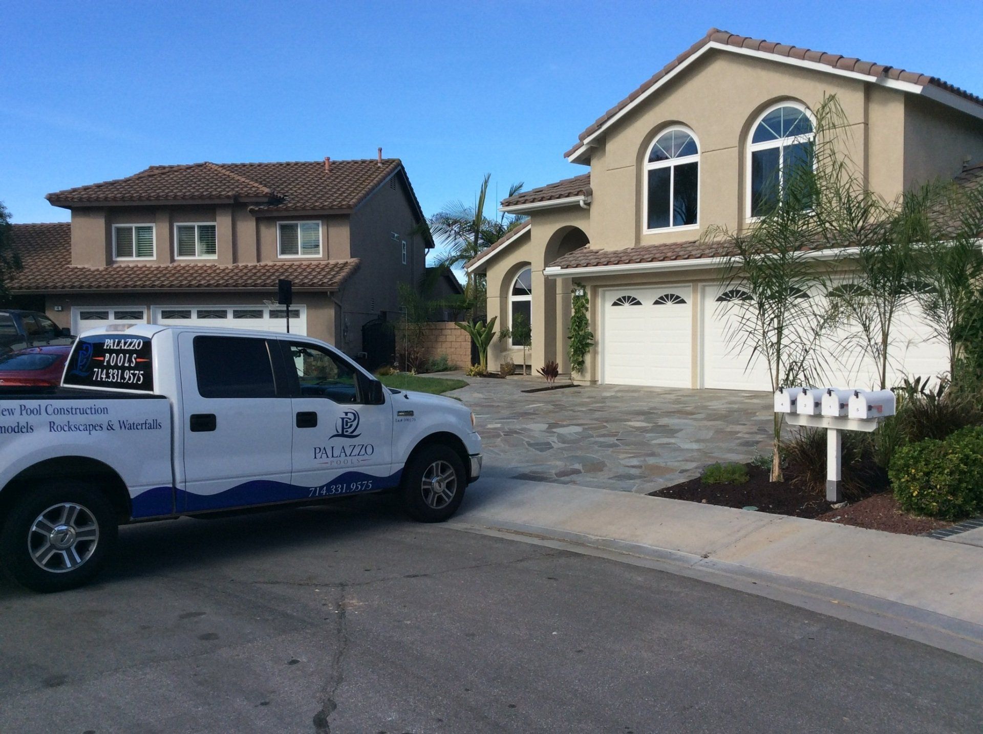 A white truck is parked in front of a large house
