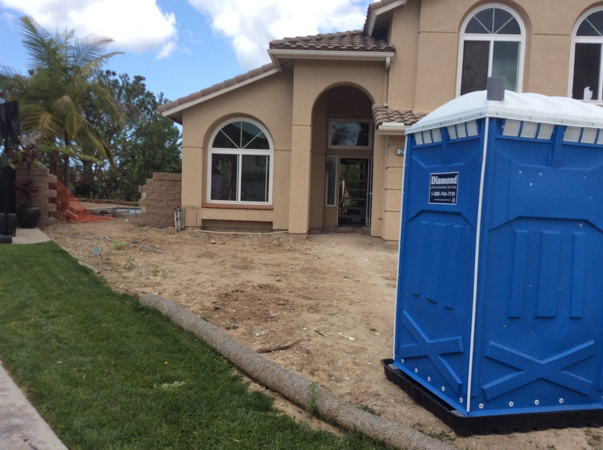 A blue portable toilet in front of a house