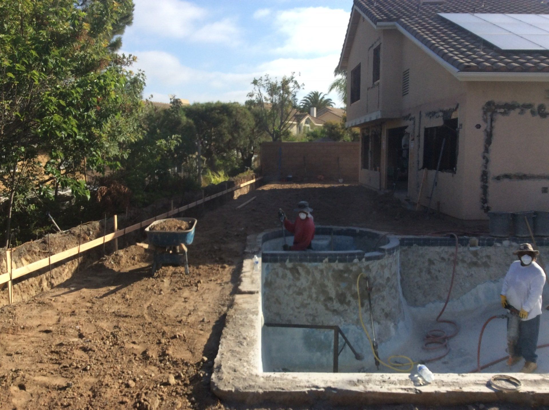 A swimming pool is being built in the backyard of a house.