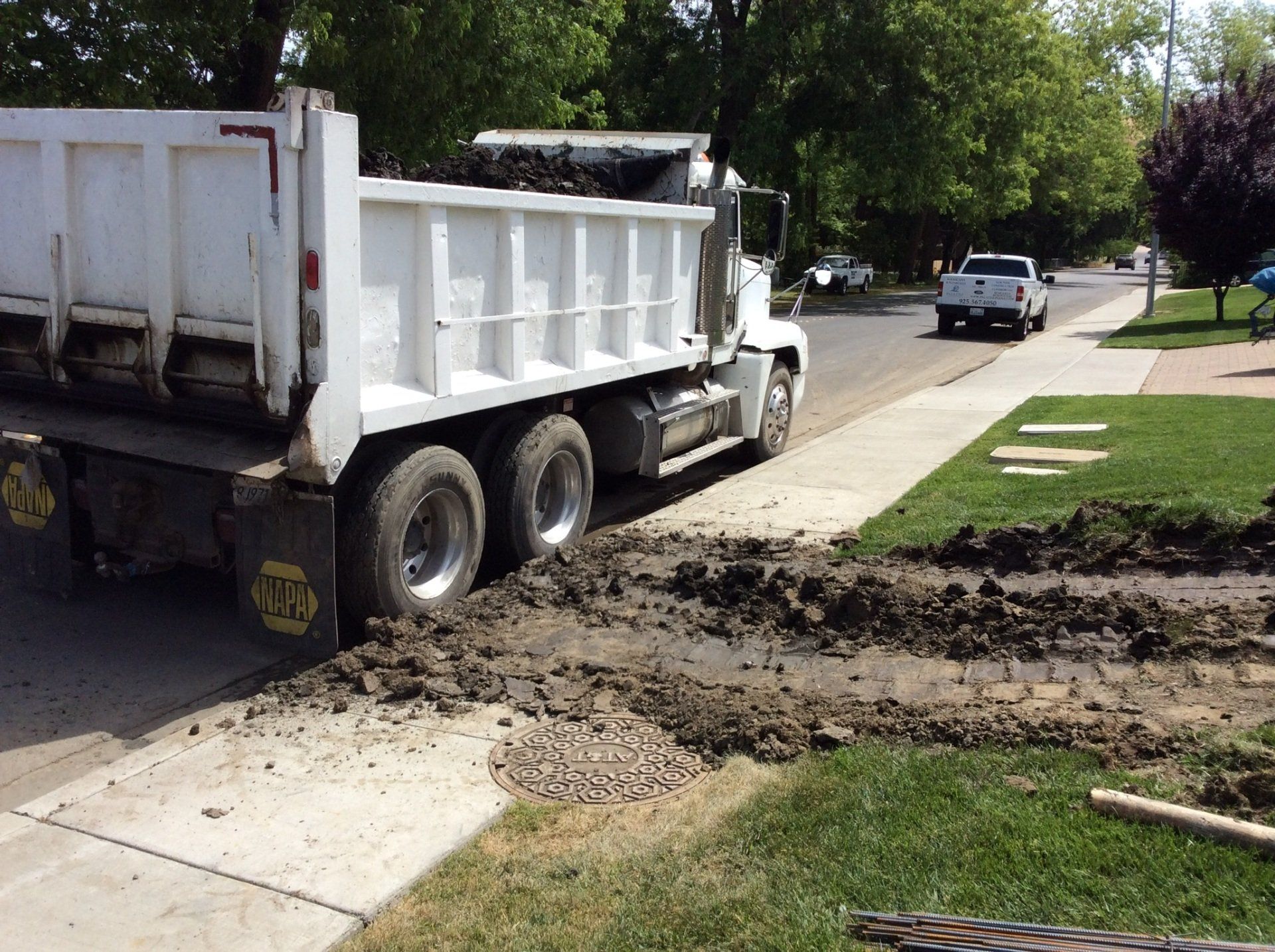 A white dump truck is parked on the side of the road