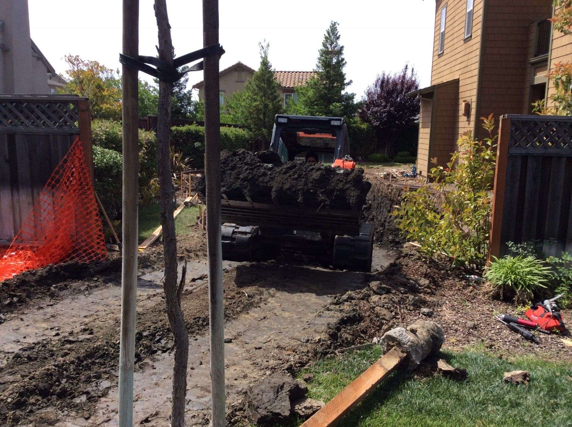 A bulldozer is digging in the dirt in front of a house