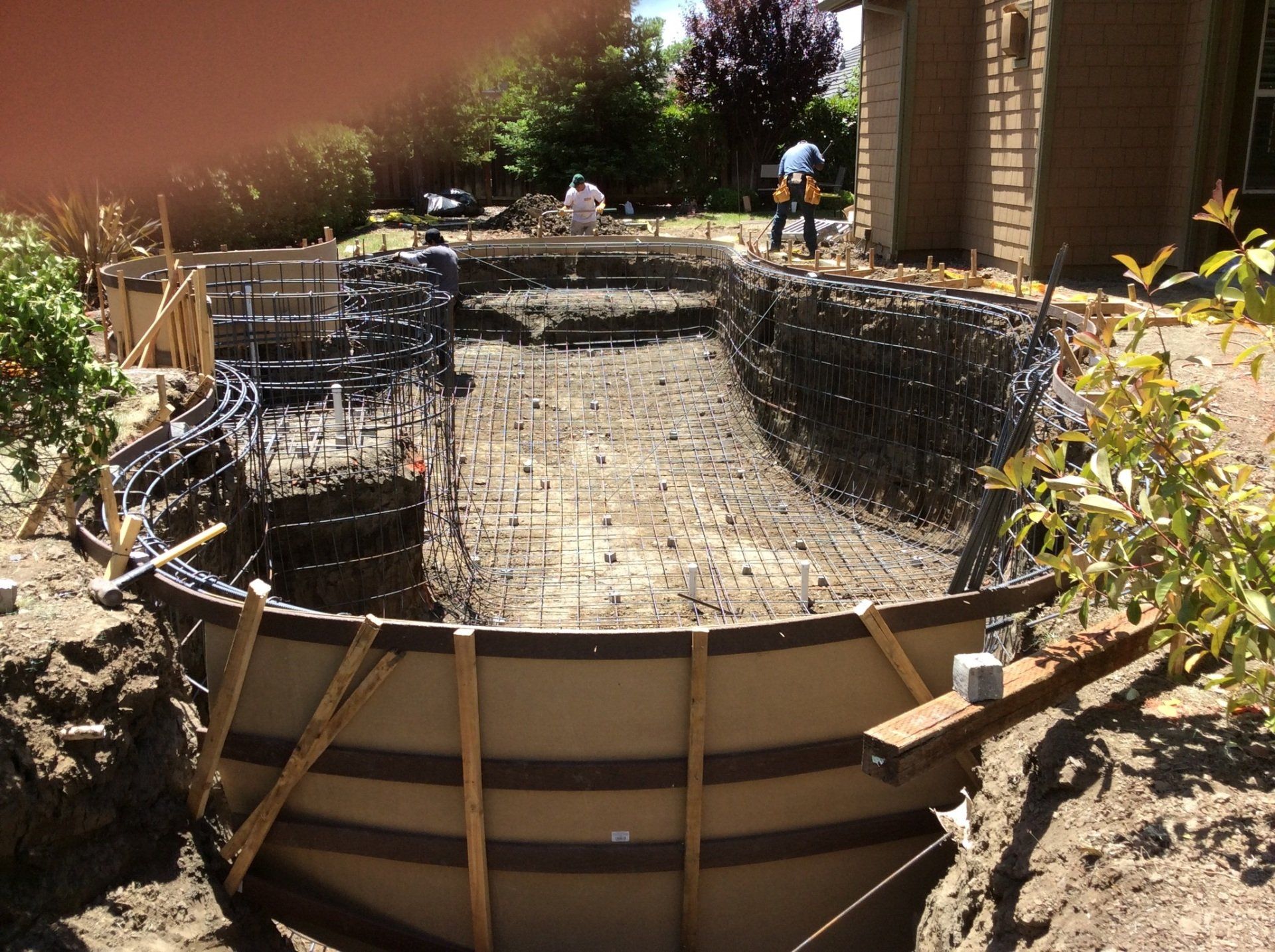 A swimming pool is being built in the backyard of a house.