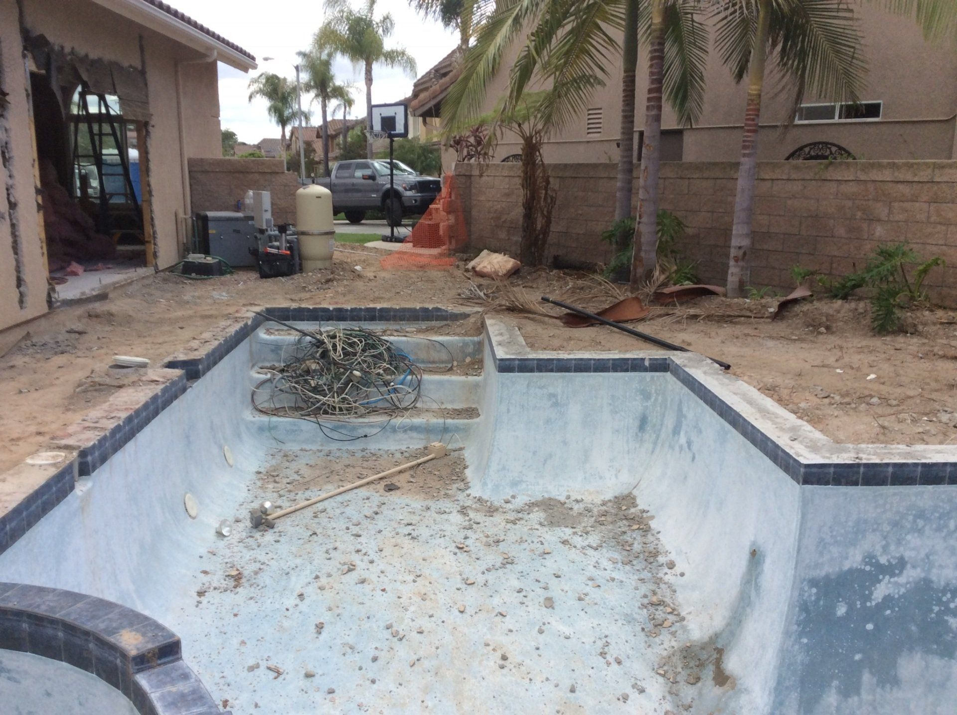An empty swimming pool with a basketball hoop in the background