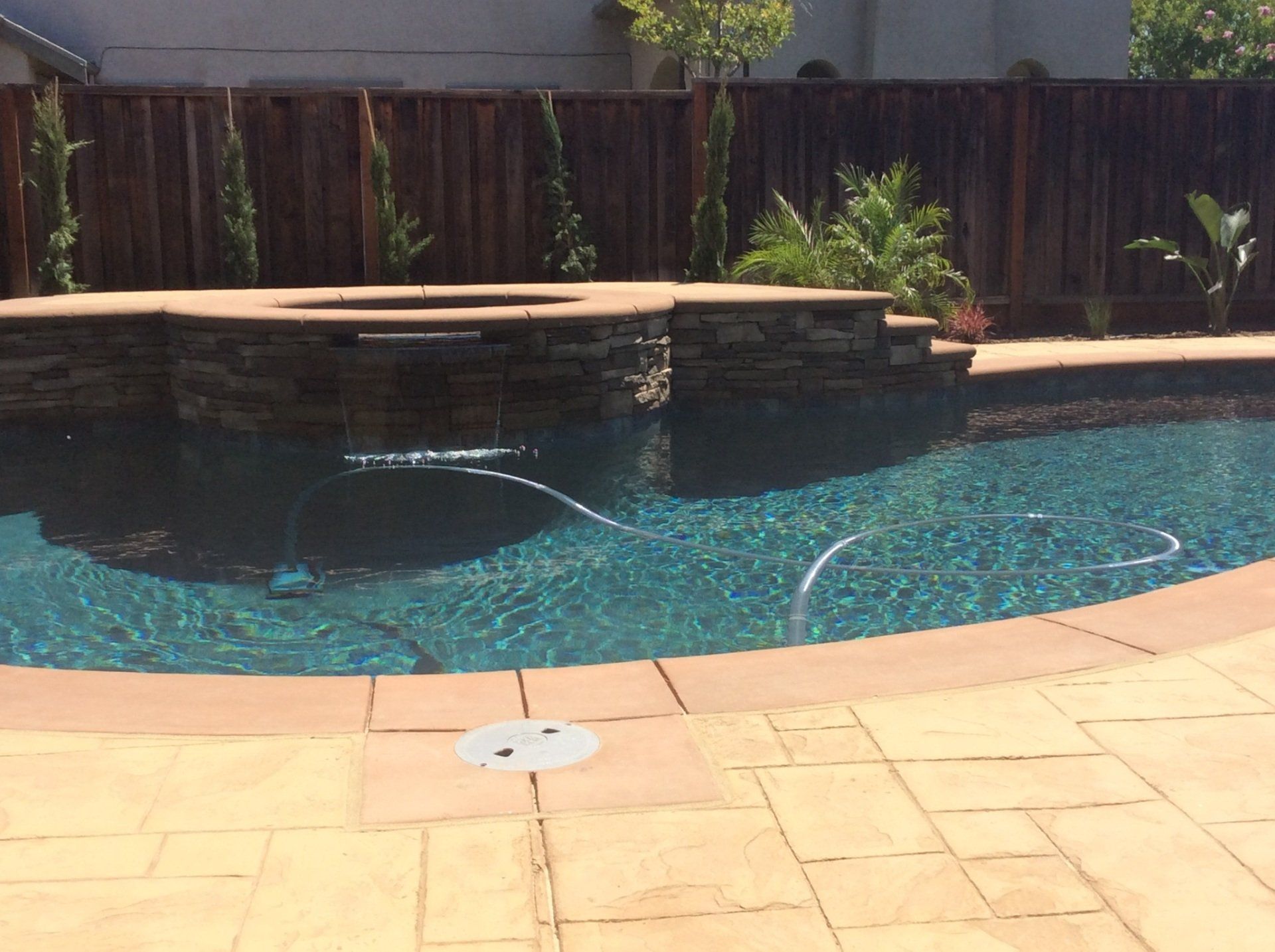 A large swimming pool with a wooden fence in the background