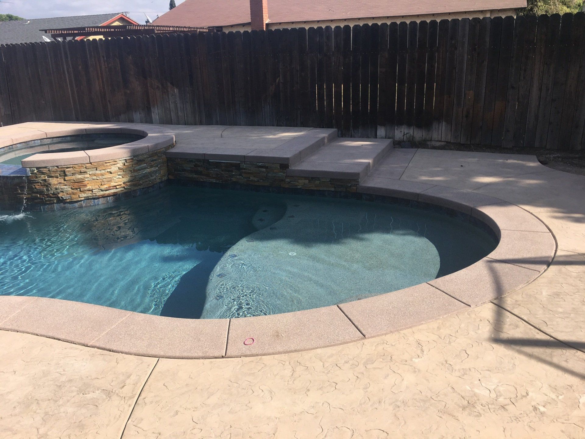 A large swimming pool surrounded by a wooden fence