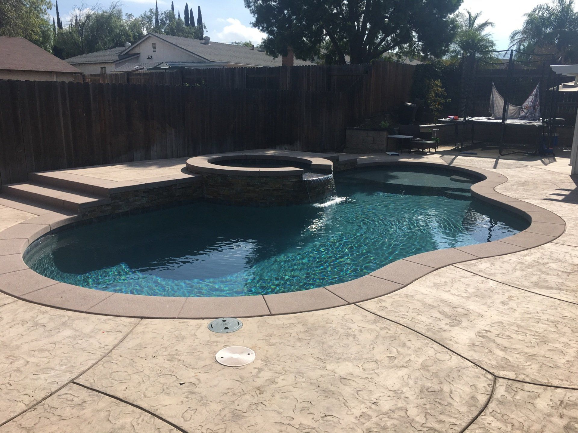 A large swimming pool is in the backyard of a house.