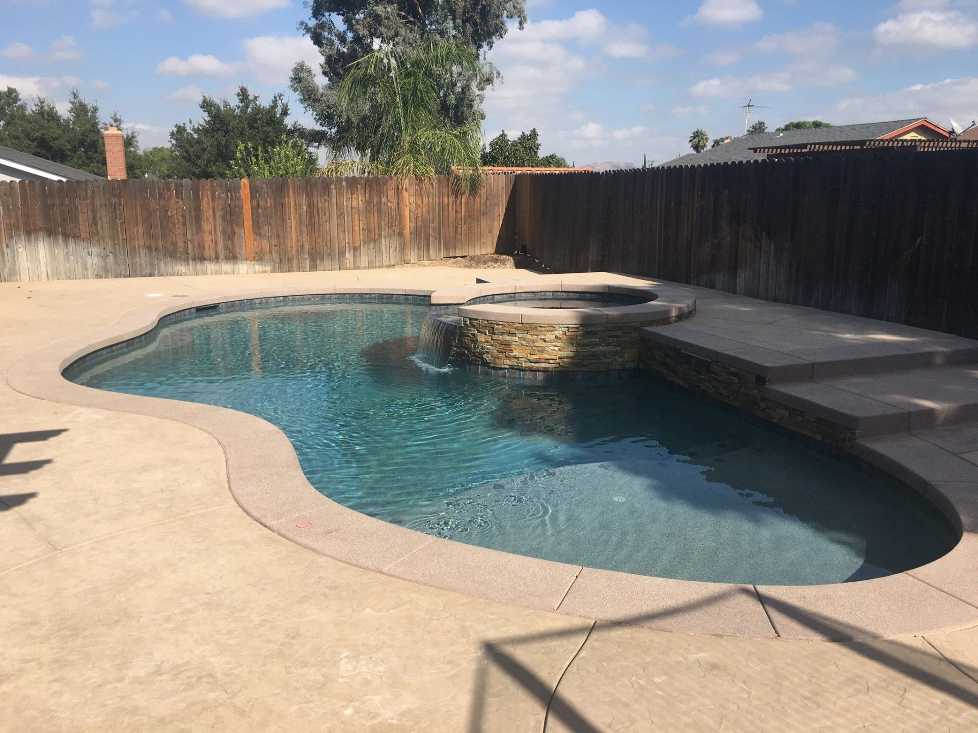 A large swimming pool is surrounded by a wooden fence.