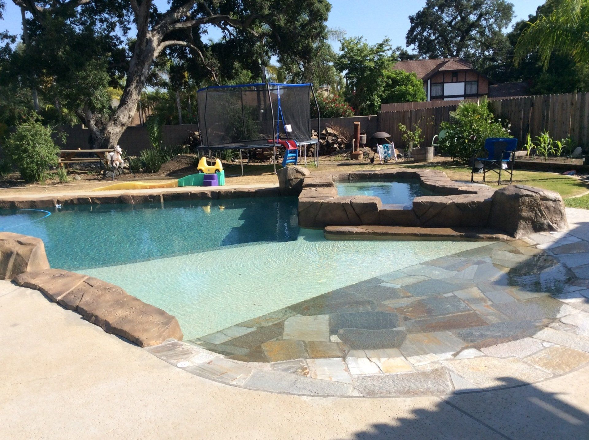 A large swimming pool in a backyard with a playground in the background