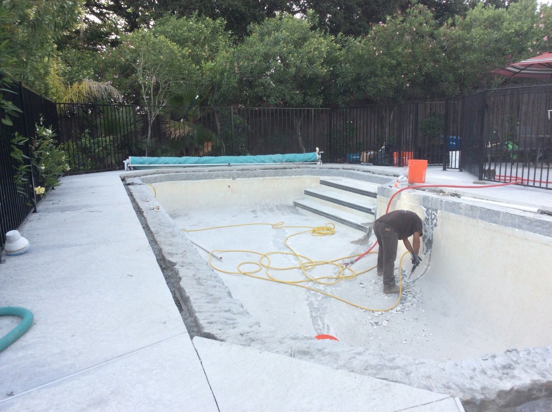 A man is working on the side of a swimming pool.