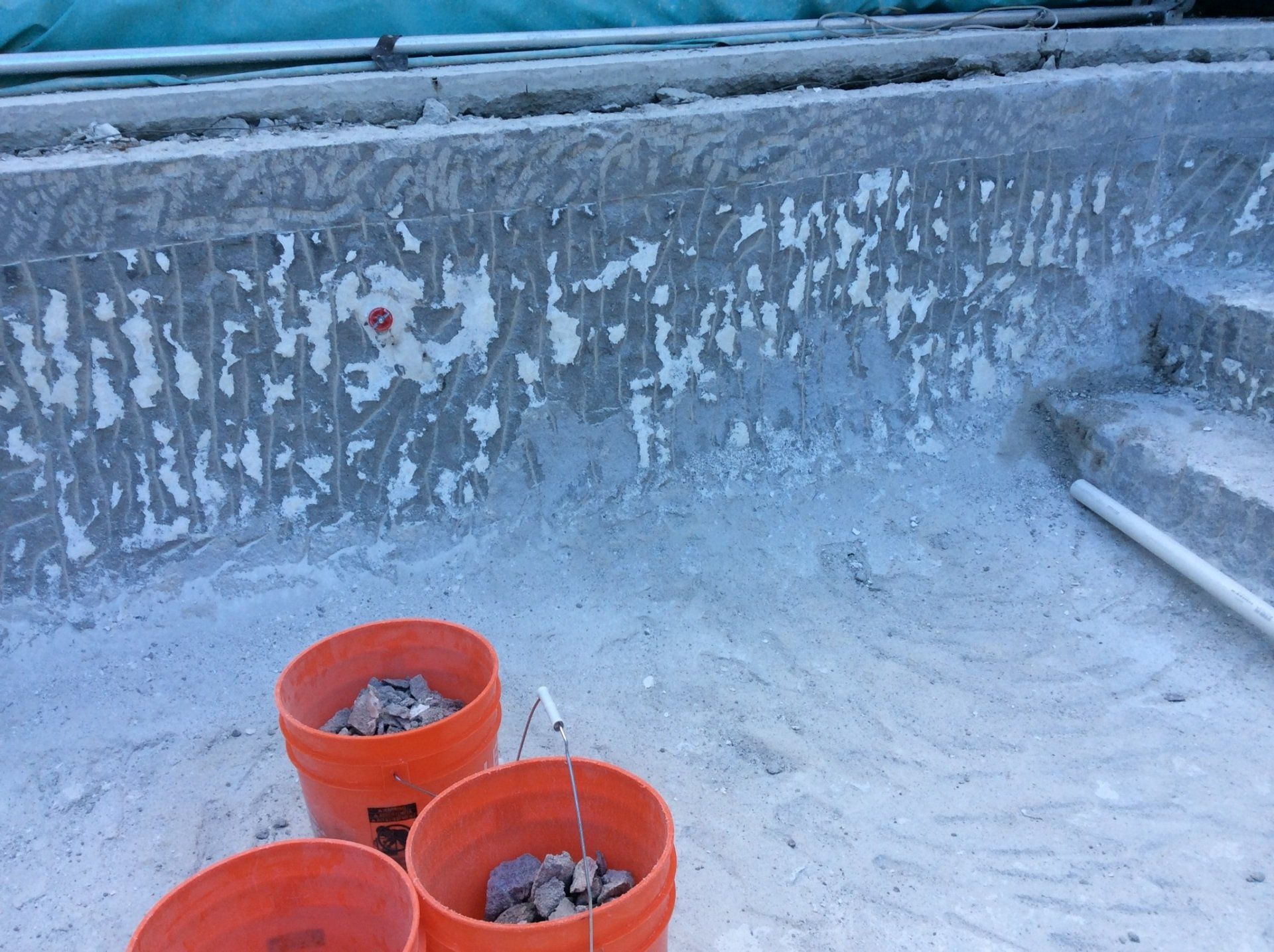 Three orange buckets filled with rocks are sitting next to a pool